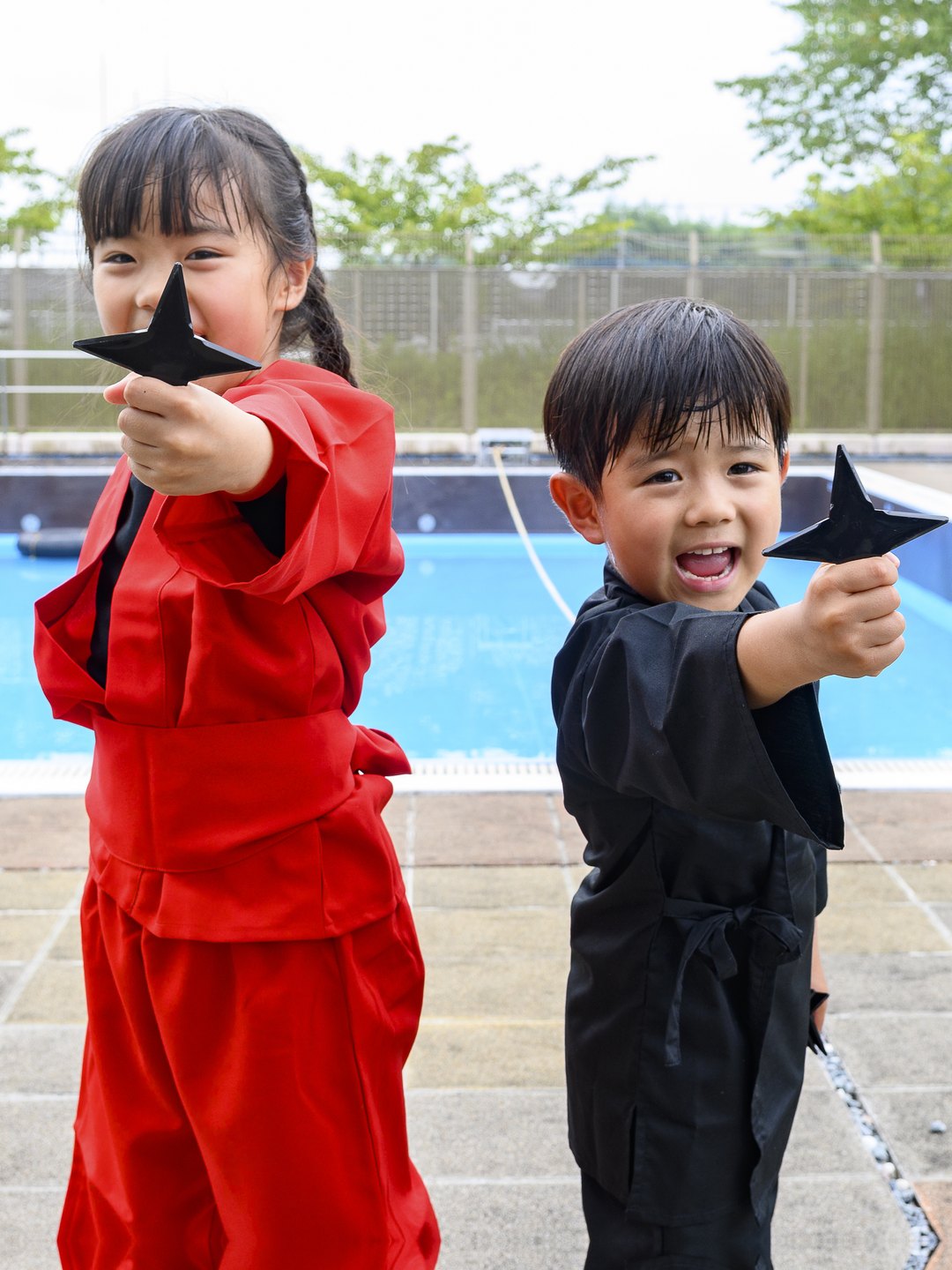 手裏剣を構える赤と黒の忍者衣装の子どもたち